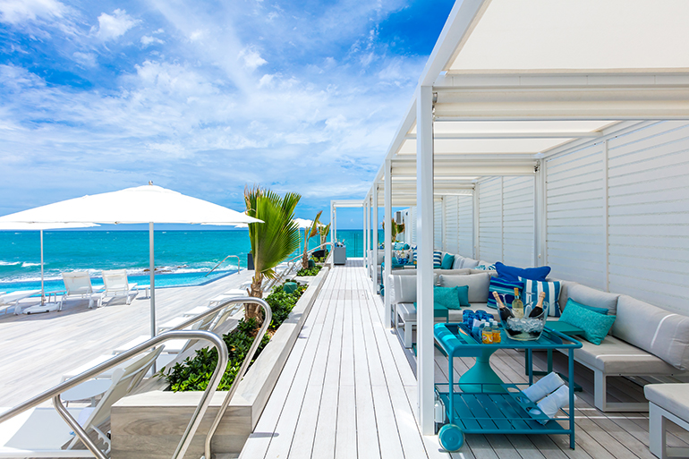 Nine cabanas anchor the pool deck with pillows in blue and teal for a pop of color in this San Juan hotel