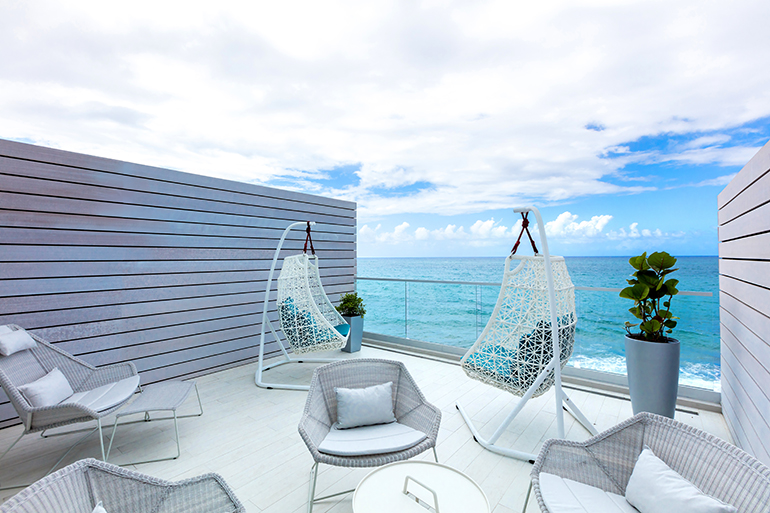 Kettal swing chairs decorate a private balcony with views of the Atlantic in this San Juan hotel