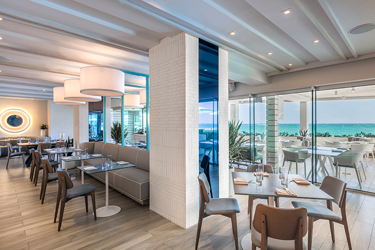 Metal posts in the dining room are tinted nautical blue, as are the mirrored porthole-style rings on the walls. 