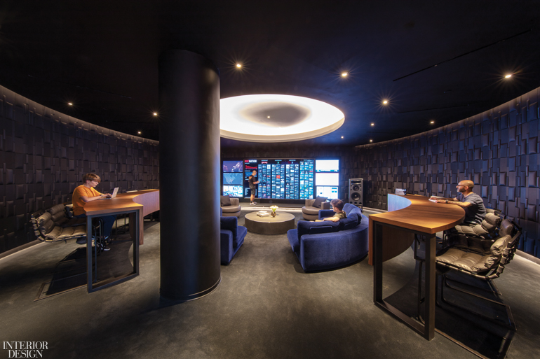 dark moody room with panel of monitors and comfy leather and velvet upholstered chairs