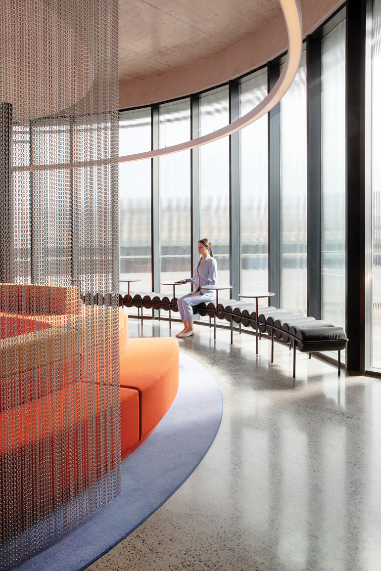 a chain-like partition separates an orange couch from more seating in Sonica's headquarters