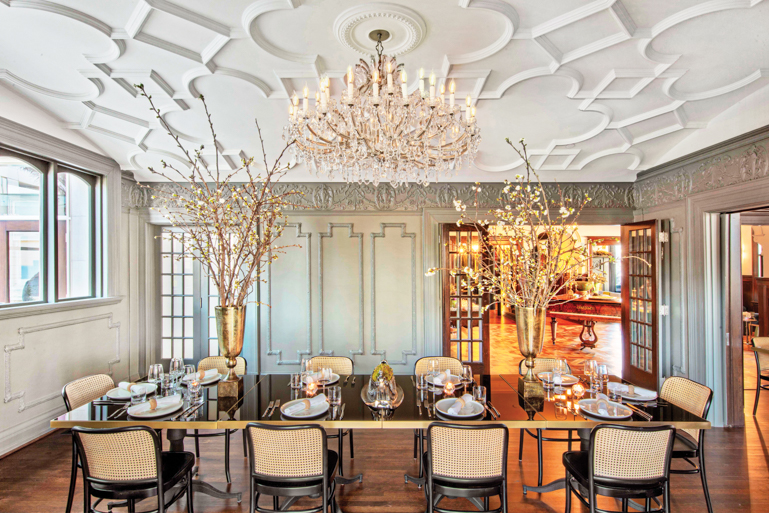 A dining table beneath a ceiling lined in crown moulding in the restaurant in La Colombe d’Or mansion 