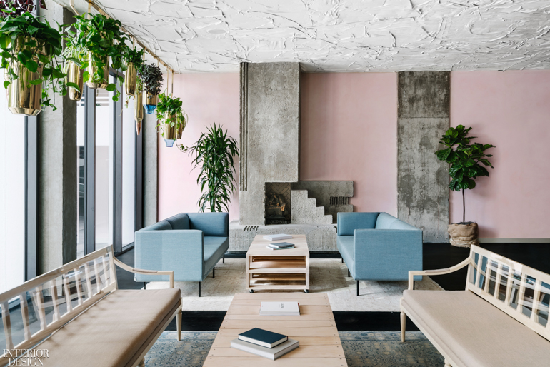 a hotel seating area with pastel pink walls and baby blue sofas