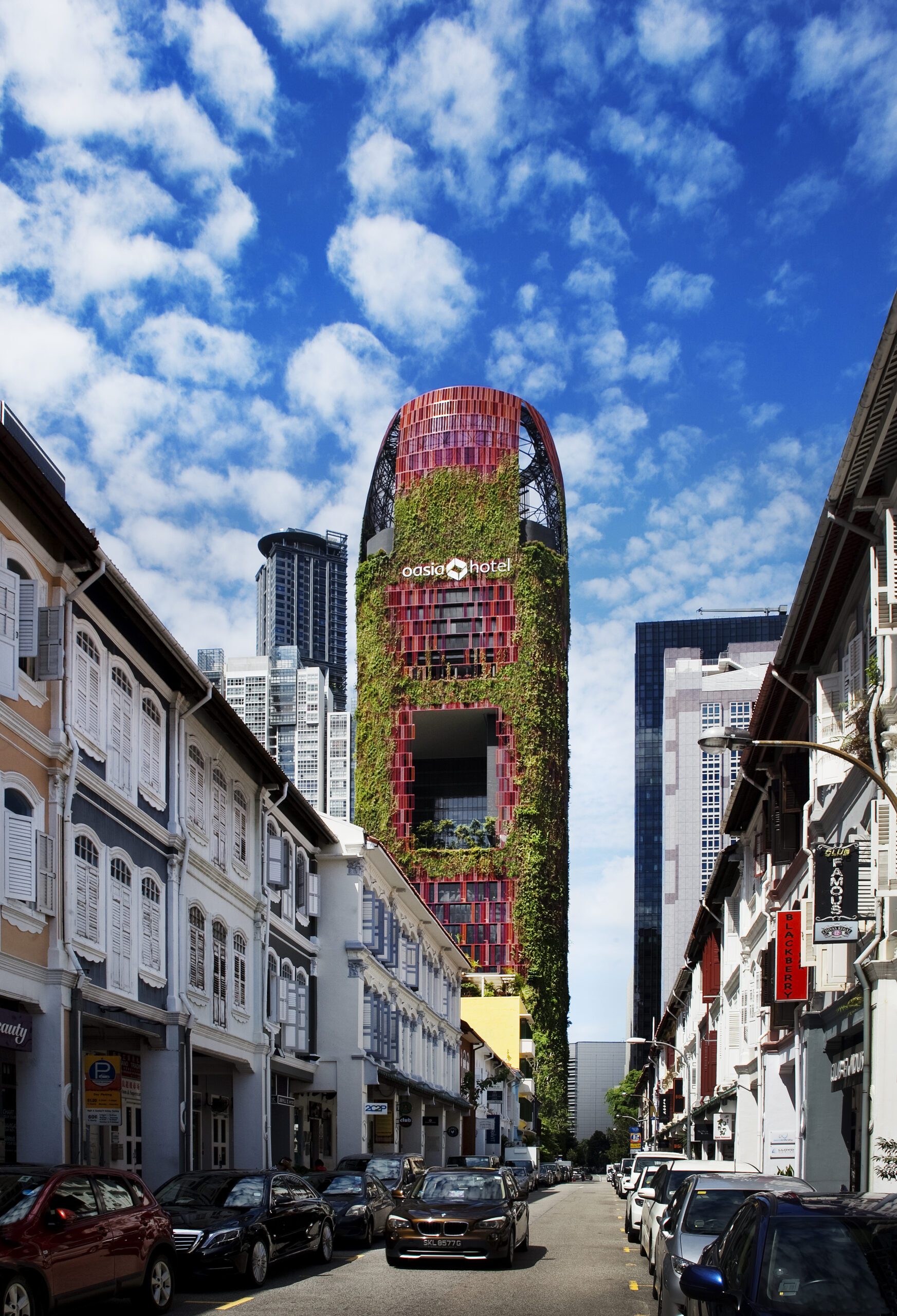 The exterior of the Oasia Hotel is covered in greenery and red brick