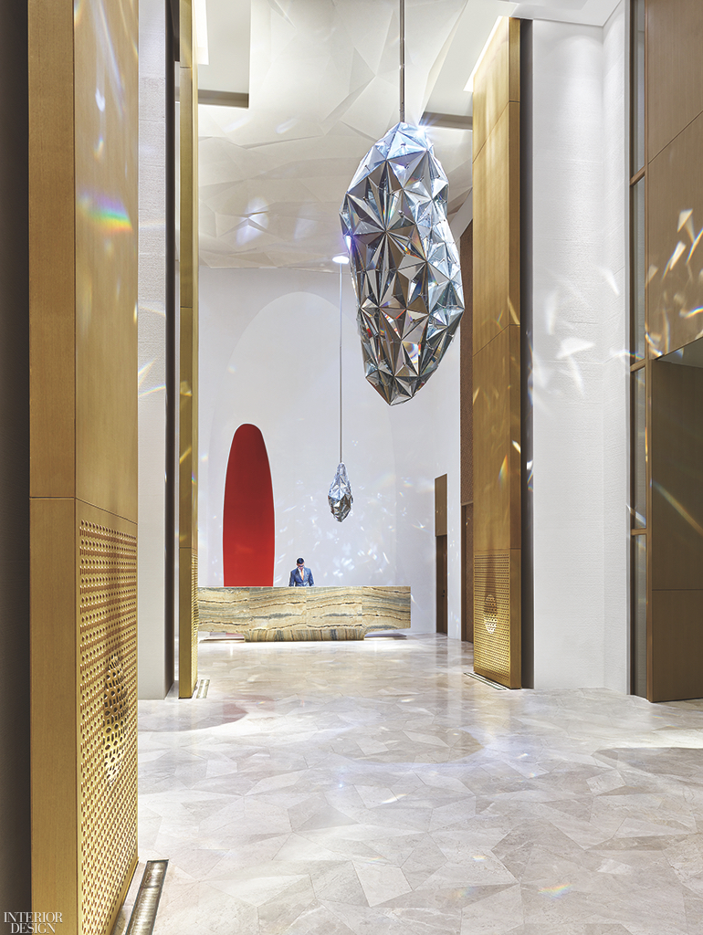 A hotel lobby with a hold reception desk and gemlike pendant lights above.