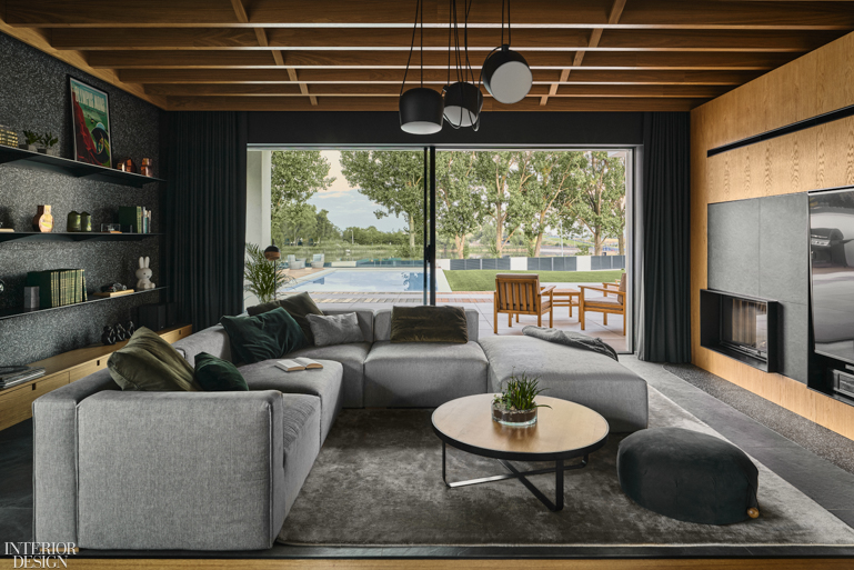 A living room with a wood ceiling and gray sectional opens to a patio and pool