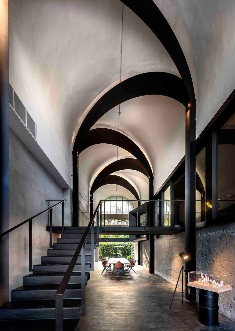 A cathedral-like ceiling with a long table and chairs opens to the outdoors