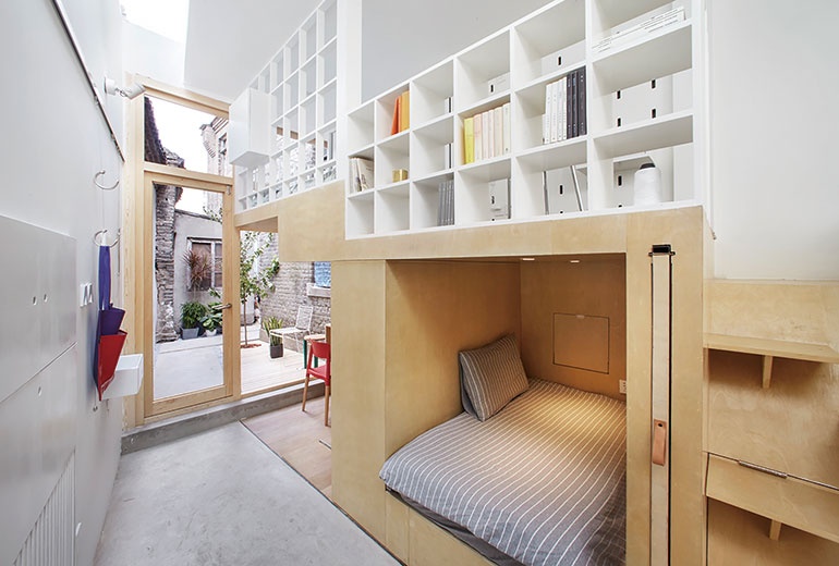 A seating nook framed by wood is tucked beneath a white bookcase