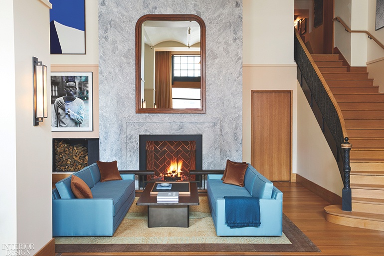 An inviting hotel lobby with a fireplace and a pair of light blue sofas. 