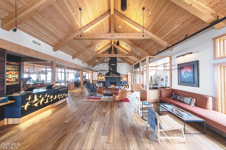 The reception area of this hotel lobby features a rustic pitched roof with exposed wood beams. 