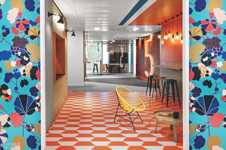 an office kitchen with blue flowery wallpaper at the entrance, decked out in orange accents