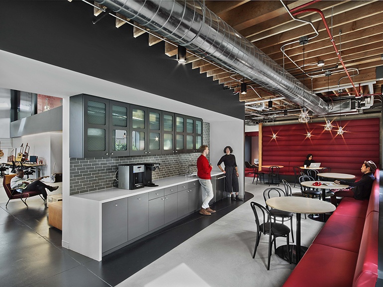 an industrial style office kitchen with gray subway backsplash and red booth seating